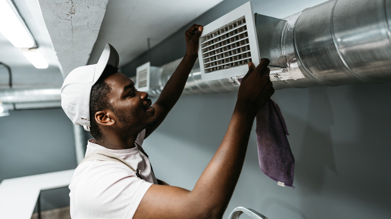 Man with white hat replacing basement air filter