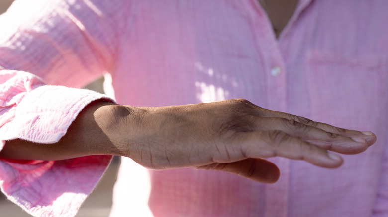 Woman holding her hand in front of her body