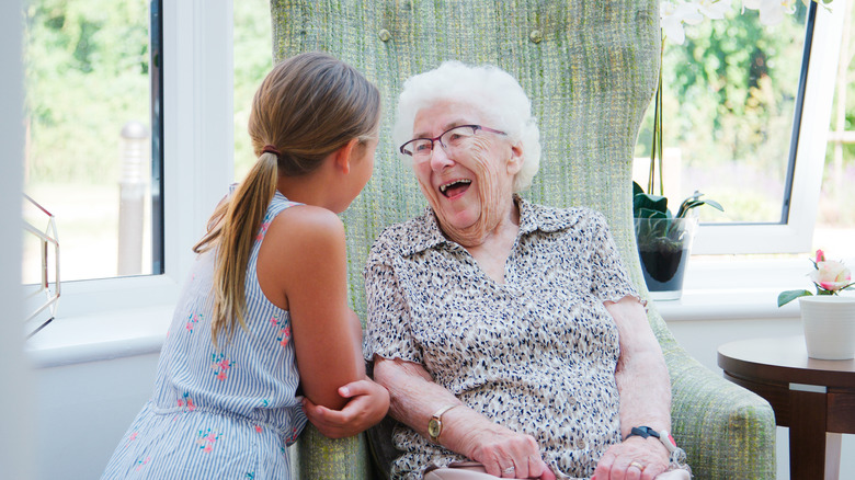 Grandmother and granddaughter smiling and laughing near open window