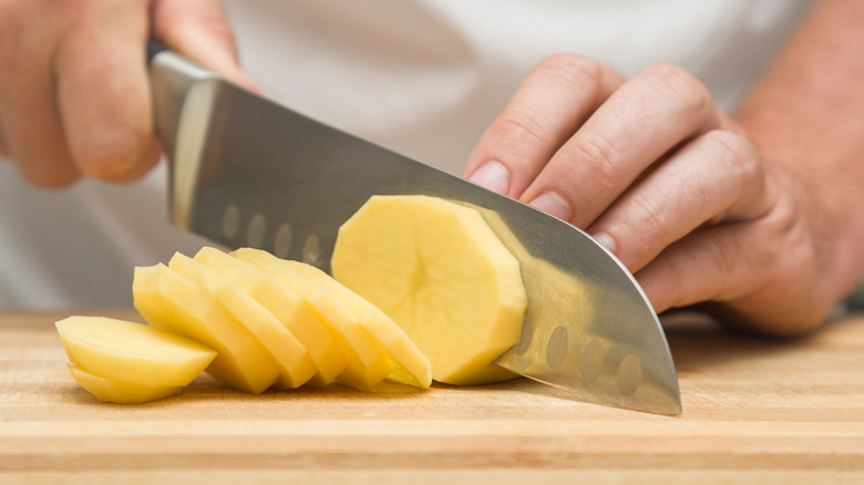 Chef cutting potato into thin slices