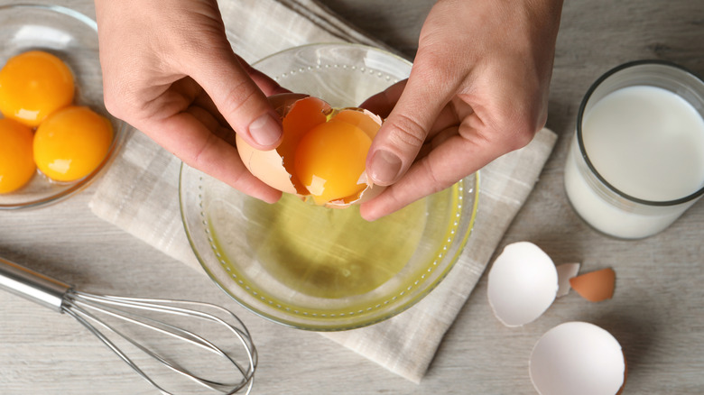 Hands cracking open an egg over a bowl