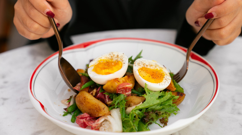 Person eating a salad with a boiled egg