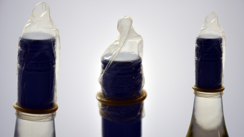 Three wine bottles with condoms over the top for an experiment