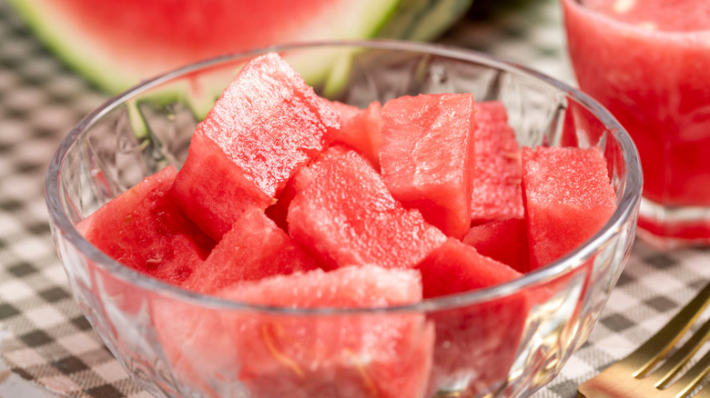 Glass bowl containing chunks of watermelon sitting on a table