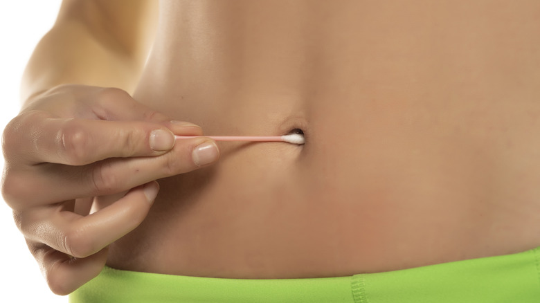 Cleaning belly button with cotton swab