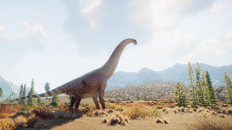 A brachiosaurus walking through dry plains with mountains and trees in background