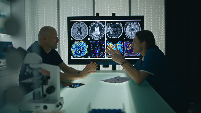Two healthcare workers having a discussion in front of a screen that display images from an MRI.