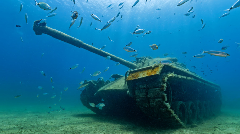 Sunken military tank serving as an artificial reef with fish swimming all around