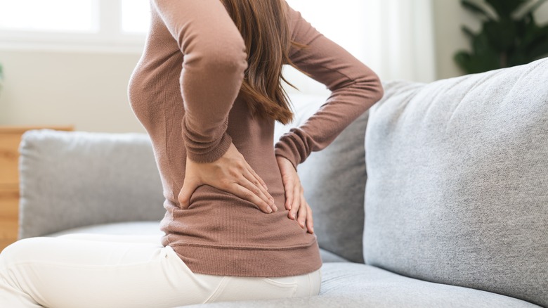 Female sitting on couch holding her lower back