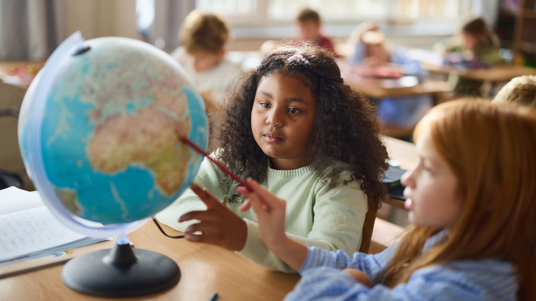 Students studying a globe in a classroom