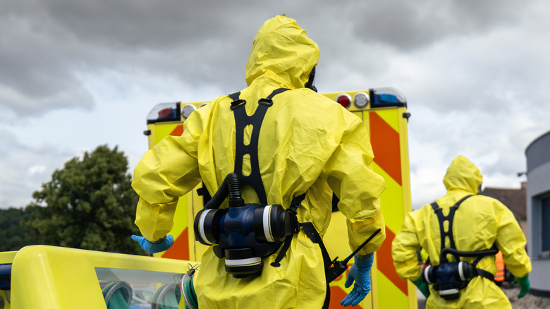A couple of people in hazmat suits walking away from the camera.