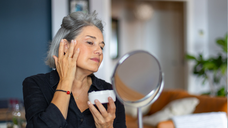A mature woman applying a skincare product to her face