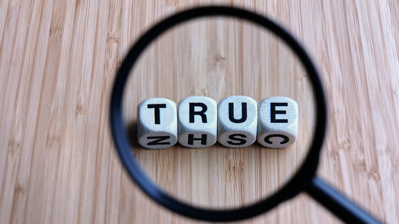 A magnifying glass centered on cubed letters that spell the word "true."