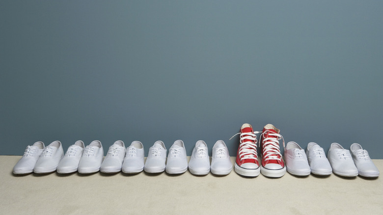 One pair of red shoes in a row of white ones.