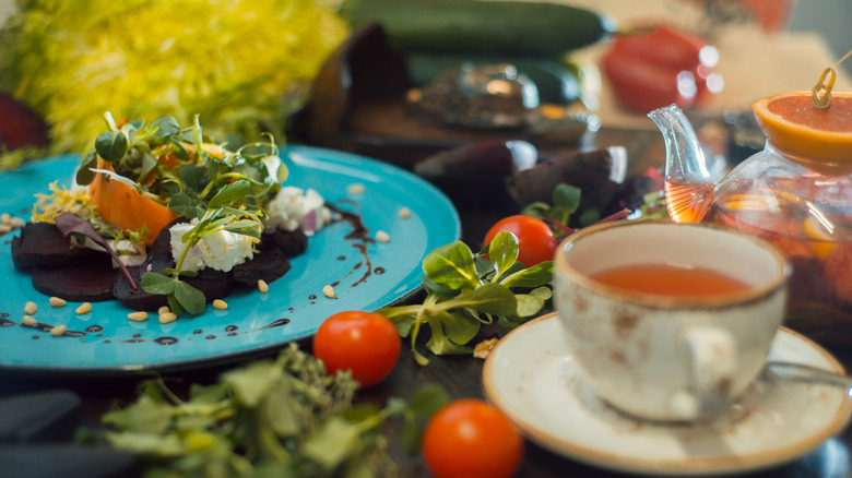 Salad next to a cup of tea on table