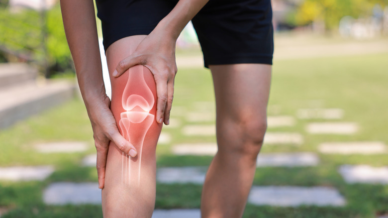 Hands holding an injured knee outdoors
