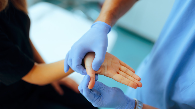 Medical professional examining a patient's hand for possible injury