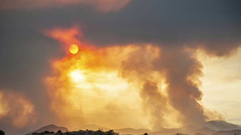 Reddish-orange sun peeks through thick clouds of wildfire smoke