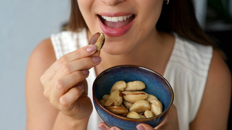 Woman eating Brazil nuts from a bowl