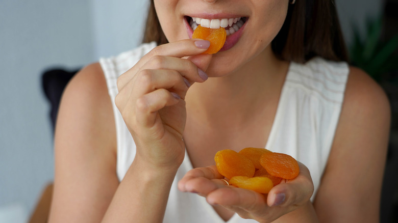 Woman eating handful of dried apricots