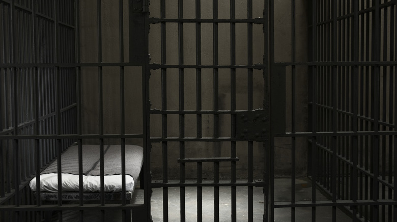 An empty prison cell with a bed.