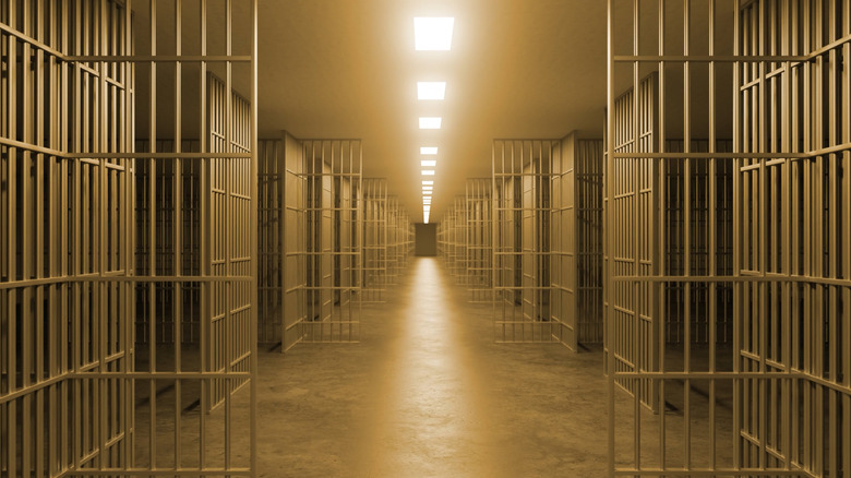 A long prison corridor with open doors.