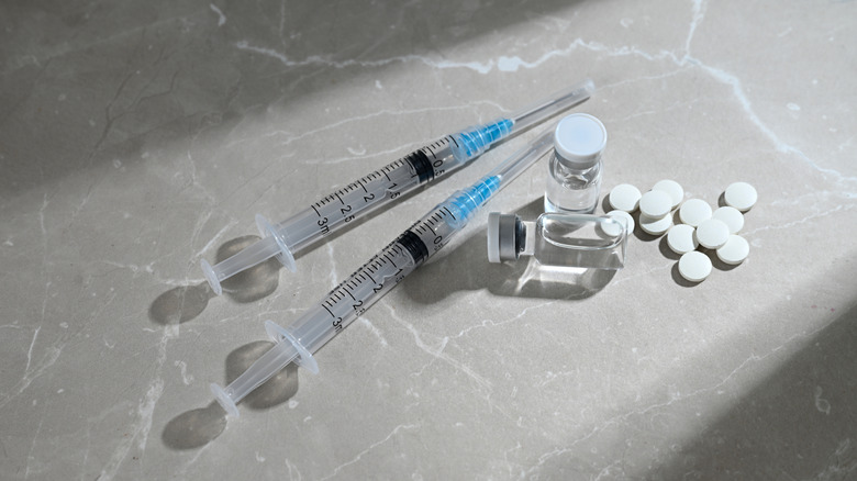 Unmarked pills and hypodermic needles lay on a table