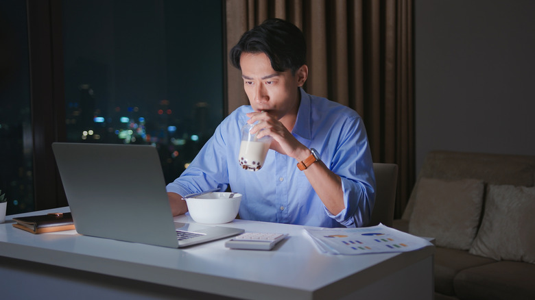 Man staying up late, eating and working on his laptop