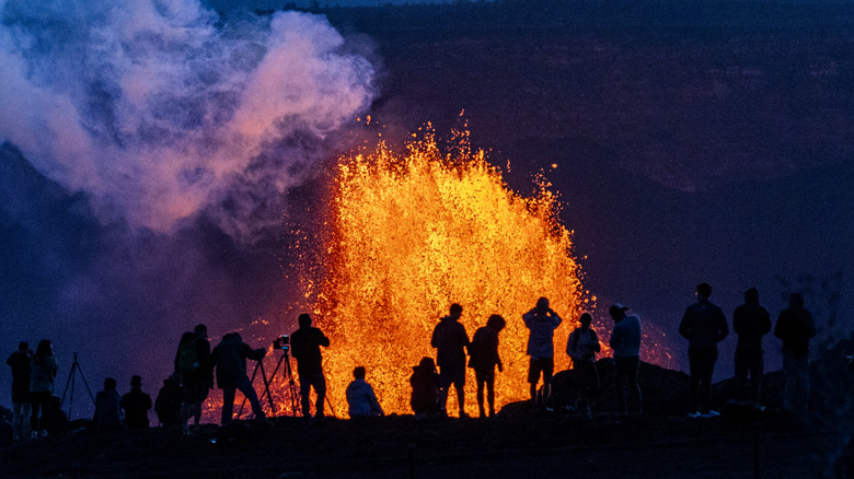 People watching as lava spews from Hawaii's Kīlauea Volcano in May 2025