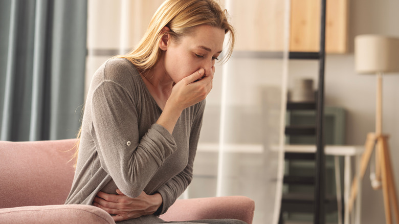 Young woman ready to vomit, feeling sick