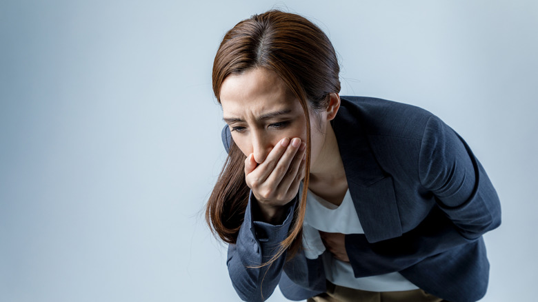 Young woman feeling nauseous, holding mouth