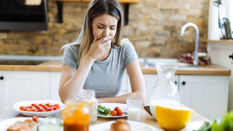 Woman feeling unwell looking at food