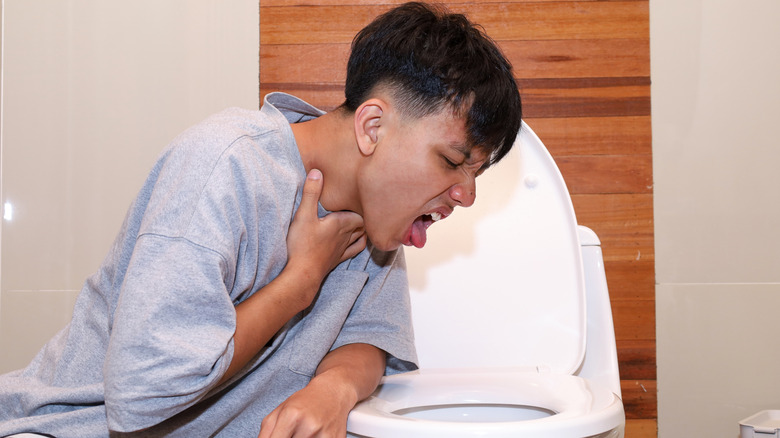 Man trying to vomit into toilet bowl
