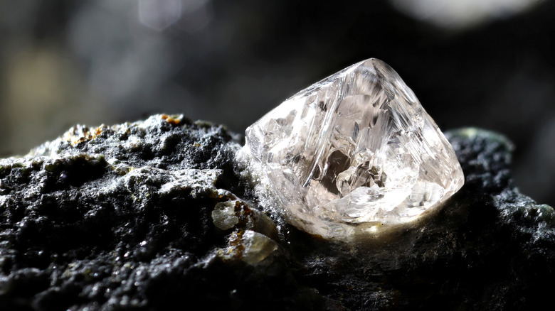 A raw diamond sits embedded in rock