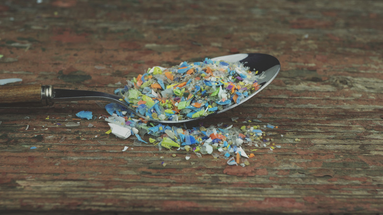 Microplastic pieces sit in a spoon resting on a wooden surface