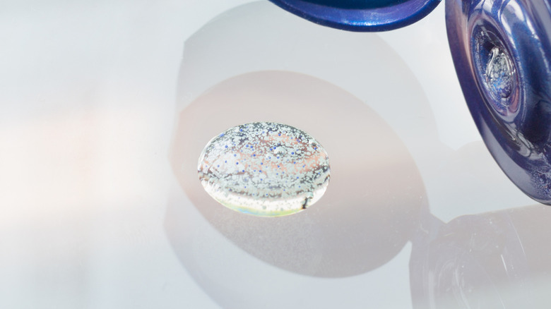 Microbeads are seen suspended in a liquid sitting on a white surface
