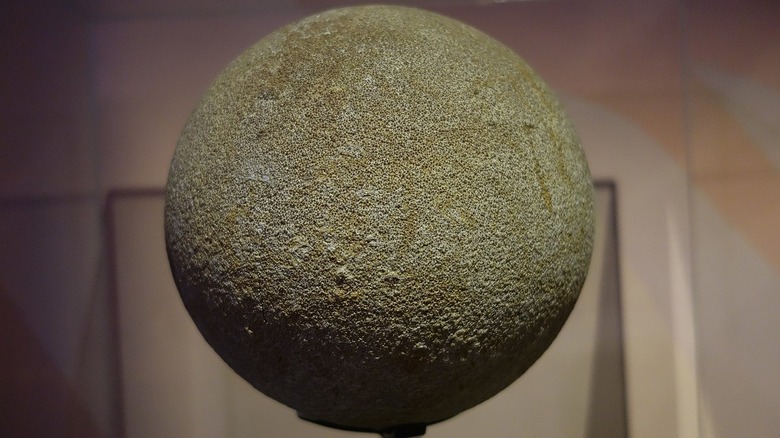 Sauropod egg on a stand that is spherical, brown, bumpy