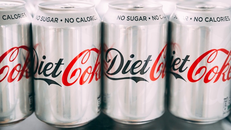 Cans of Diet Coke lined up in a refrigerator