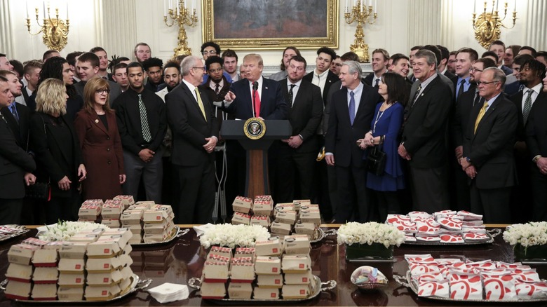 President Donald Trump presenting table of fast food to a crowd at the White House