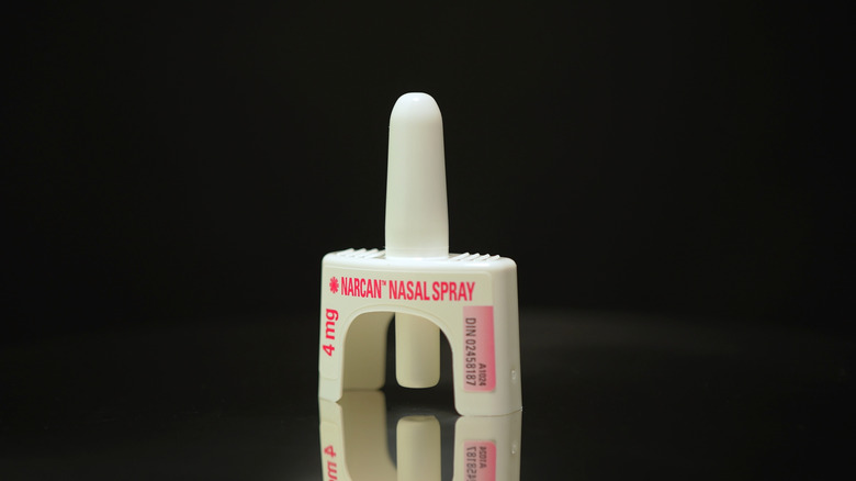 A narcan nasal spray is seen against a black background