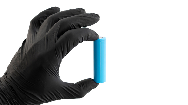 A gloved hand holds a lithium-ion battery