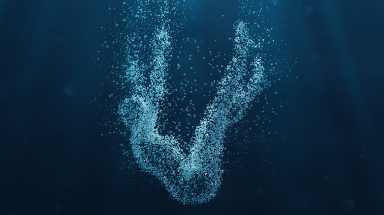 Silhouette of falling person made of bubbles in dark water