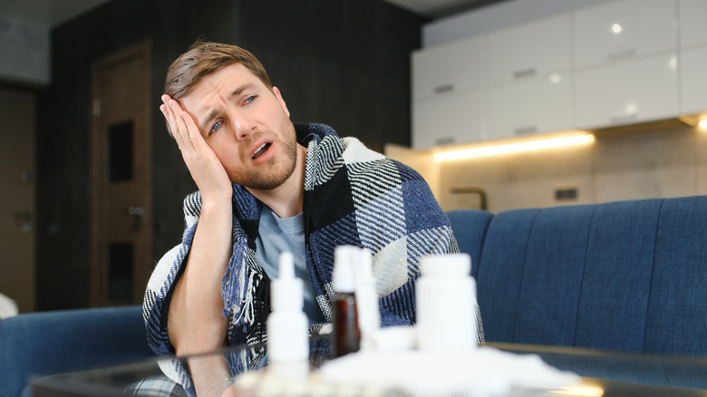 Sick man sitting before a table full of medications