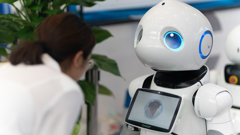 A woman interacting with a facial recognition robot