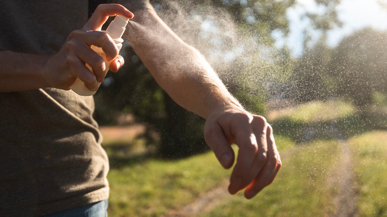 Person spraying mosquito repellant on arm