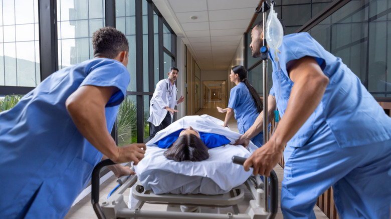A team of medical care workers rush a patient on a gurney to the emergency room