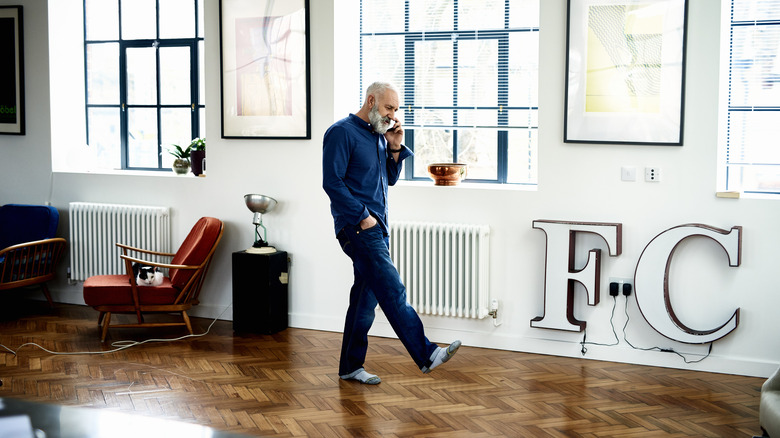 A man paces around a room while talking on the phone
