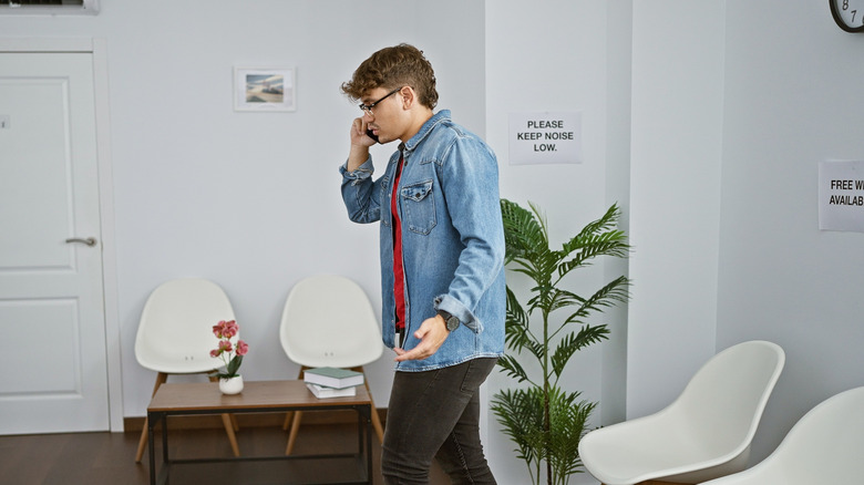 A man walking around a waiting room while talking on the phone