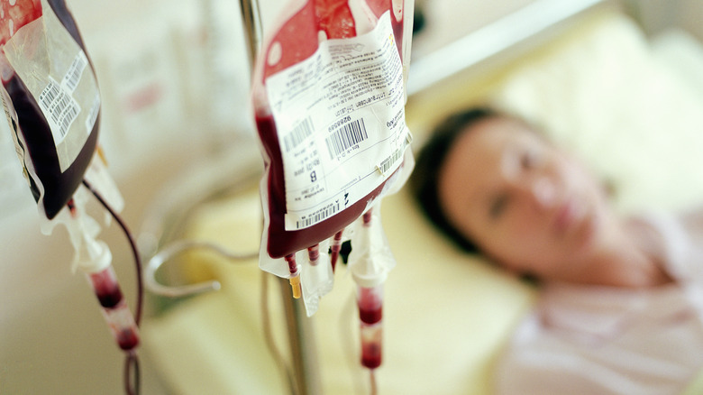 Woman in hospital bed is looking at an IV bag