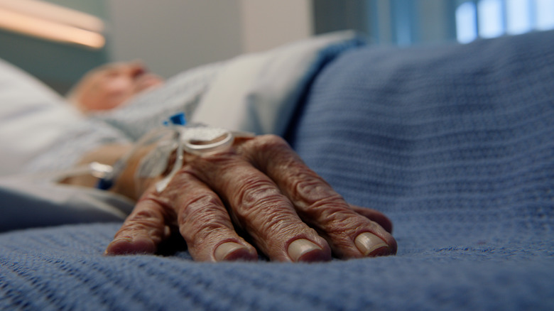 An elderly man is lying in bed
